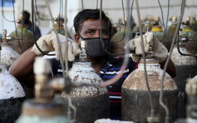 Ein indischer Arbeiter füllt Sauerstoffflaschen für Coronakranke ab.